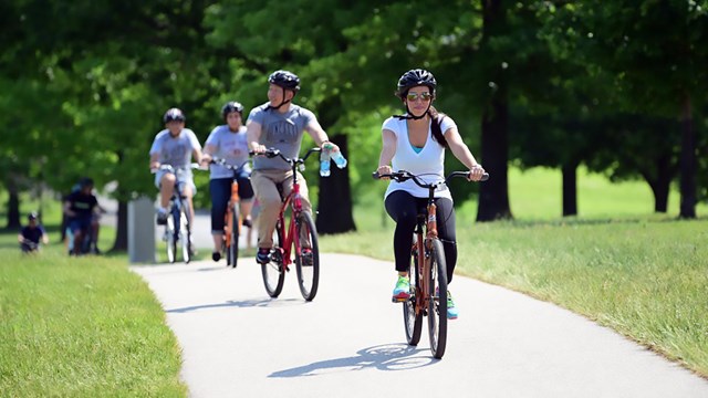 people riding bicycles on a paved path